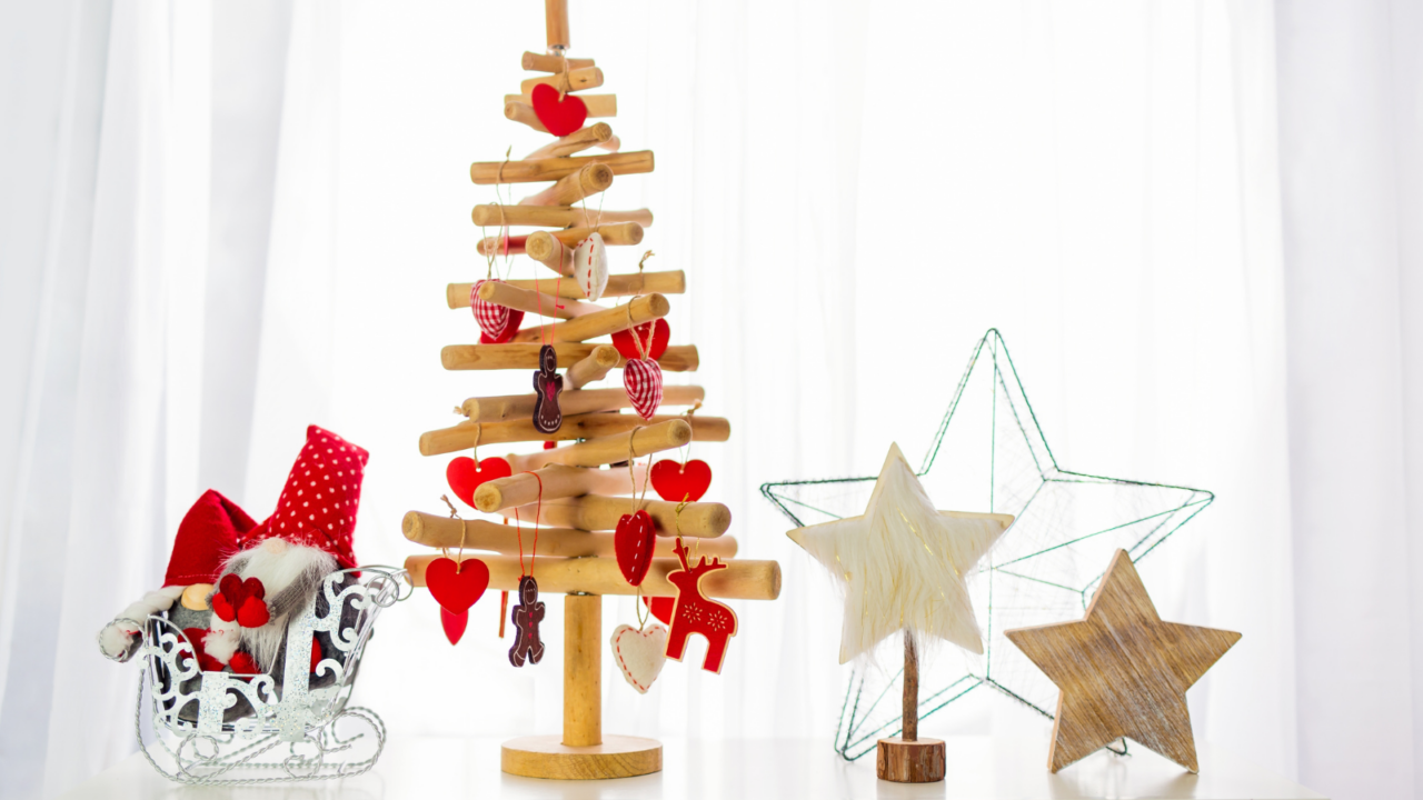 Closeup of Christmas decorations on a white background. A small wooden Christmas tree, 2 wooden stars, and a metal star.