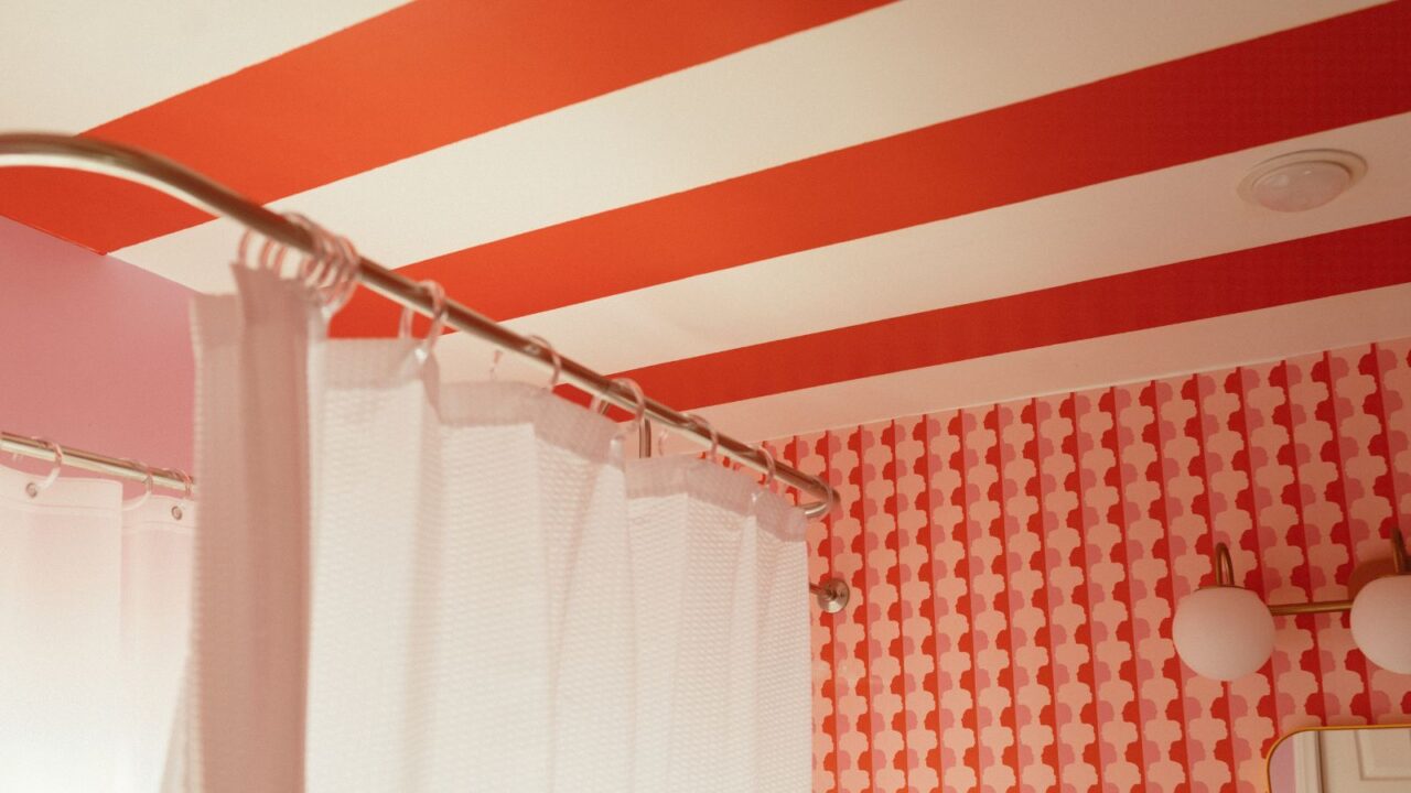 Bathroom with red and white striped ceiling and patterned wallpaper.