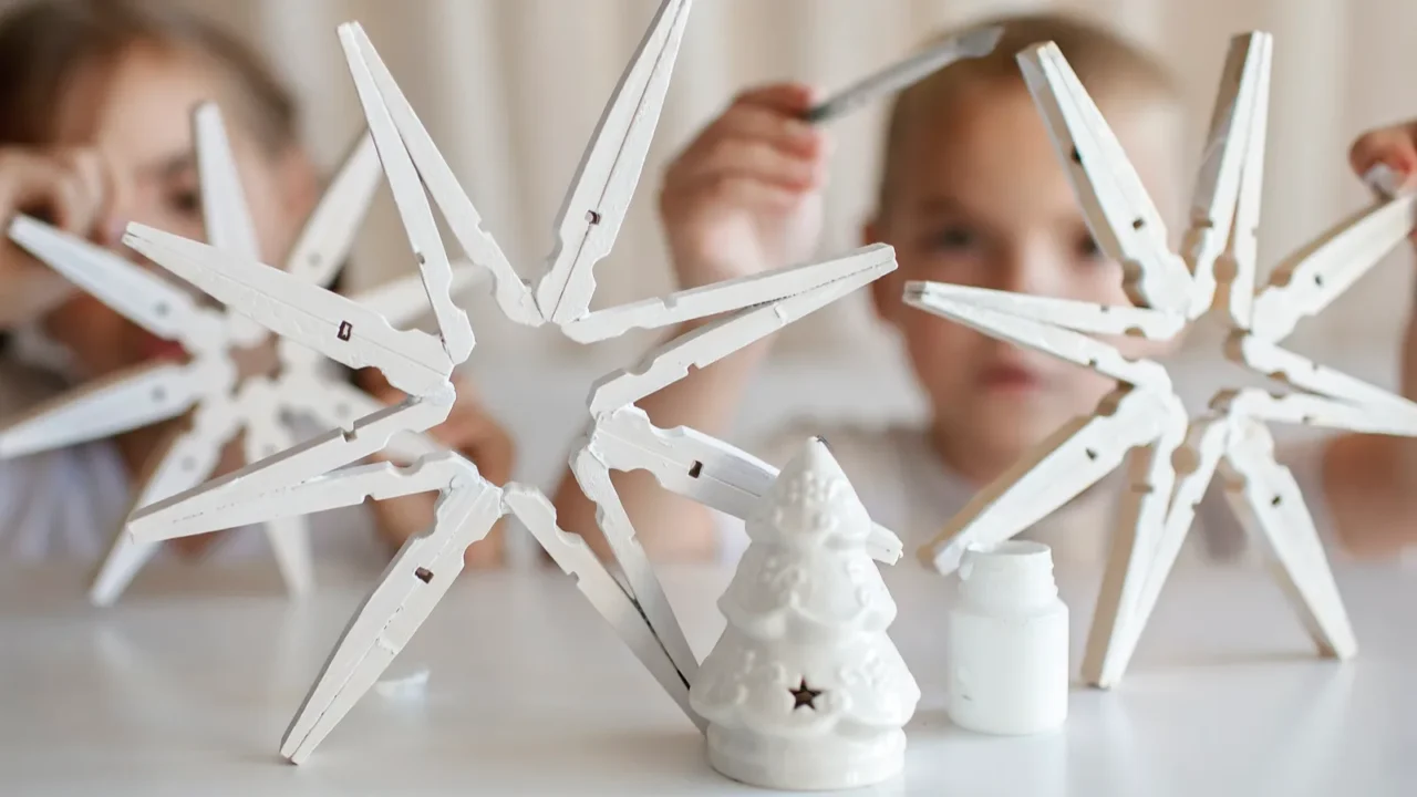 siblings boy and girl paint wooden snowflakes from clothespins with