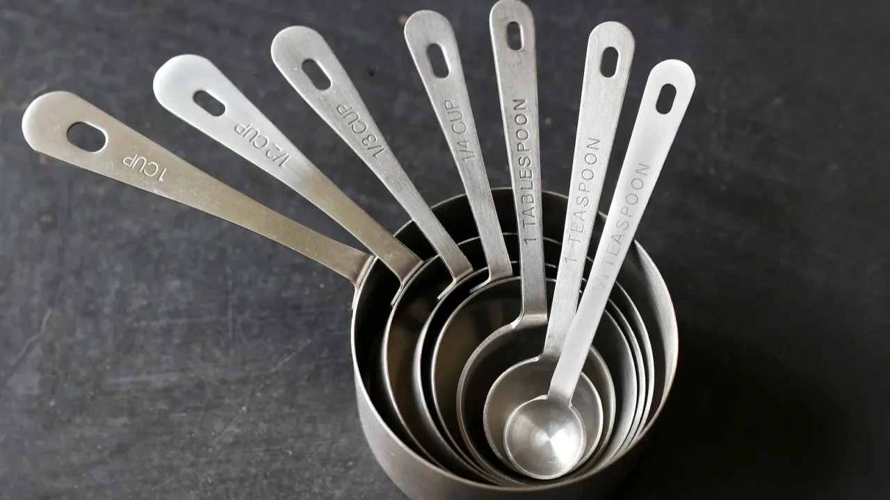 silver measuring cups stacked on black background