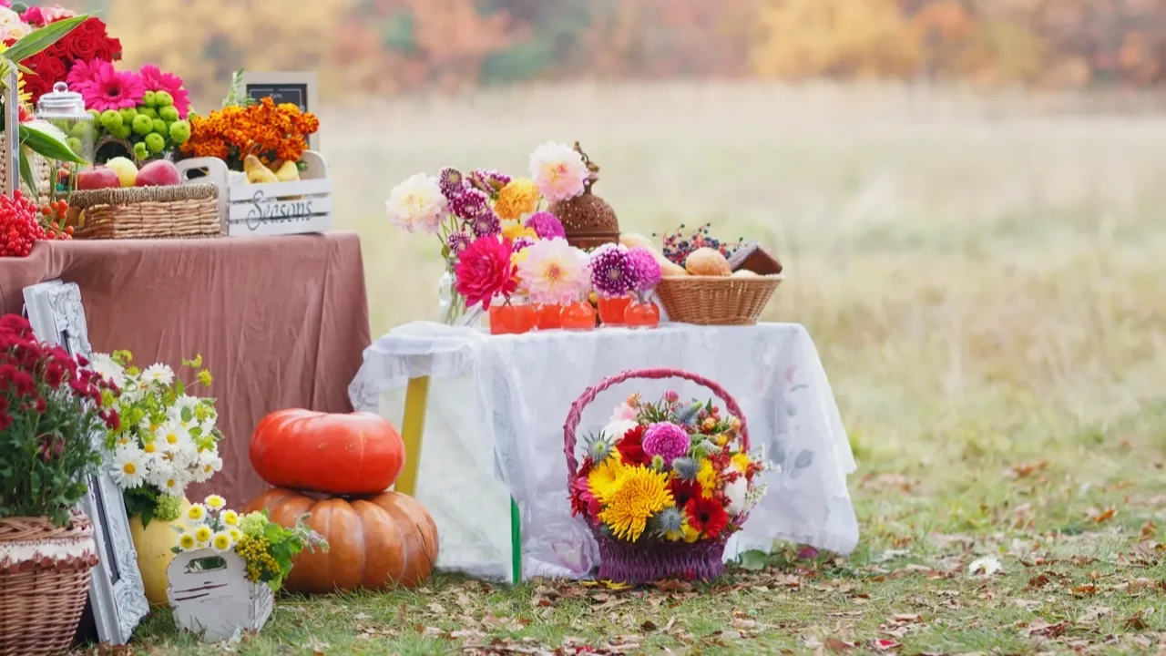 Tables decorated with autumn fruits and flowers in baskets.