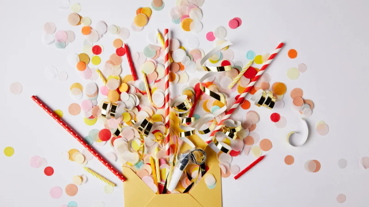 top view of confetti pieces and yellow envelope on white