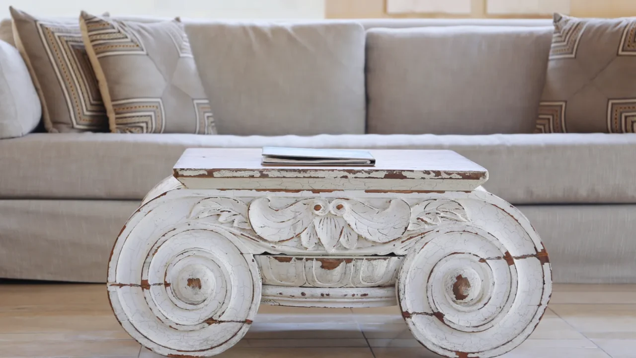 White weathered and vintage wooden table with a soft color sofa and cushions at the back.