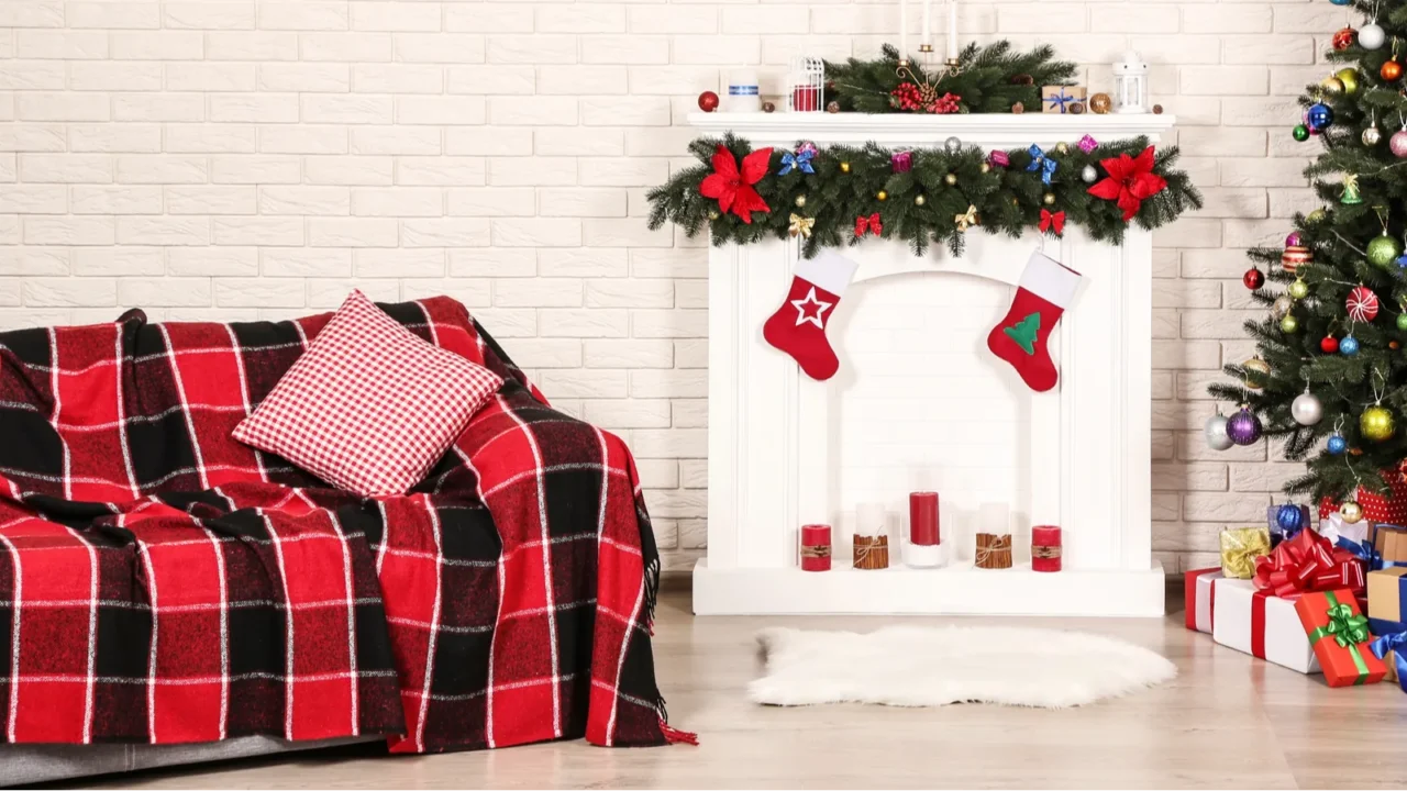 A living room interior with decorated fireplace, faux fur rug, and a sofa with plaid blanket.