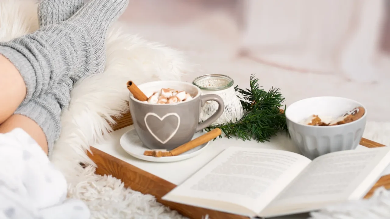 woman lies with cup kako hot chocolate marshmallows book tray