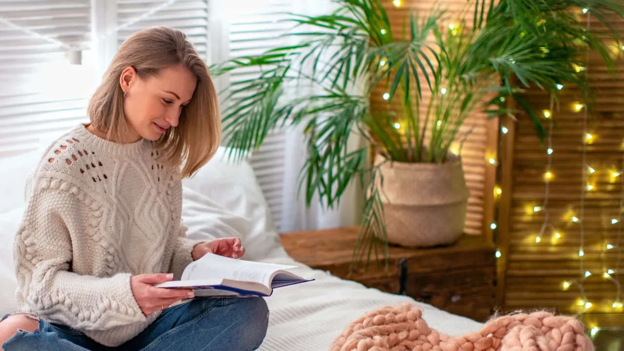 A woman reading a book on the bed.