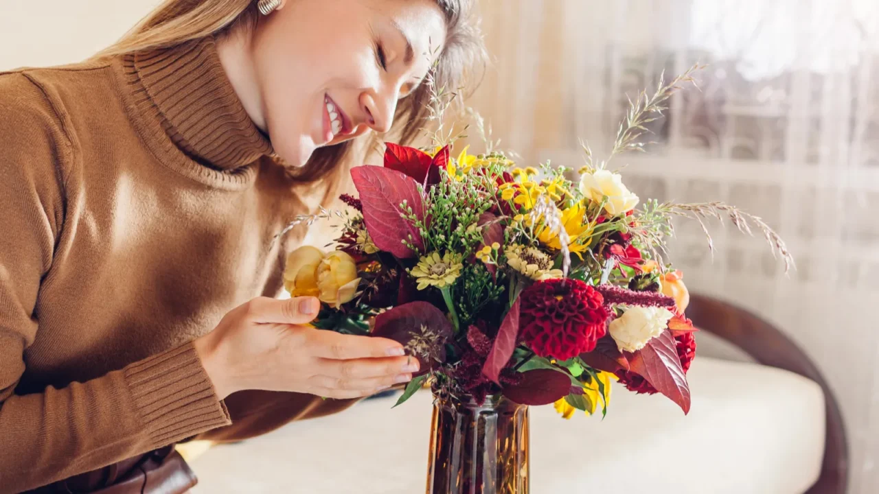 A woman smells fall bouquet made of sunflowers, zinnia, roses, and dahlias.