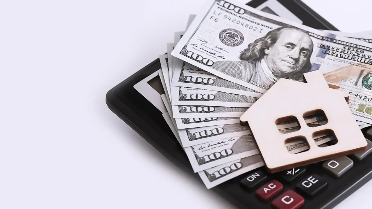 wooden house with dollars banknotes and calculator on white background