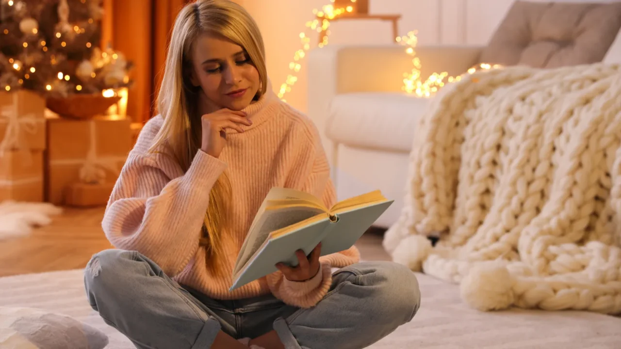 young woman reading book on carpet at home christmas celebration