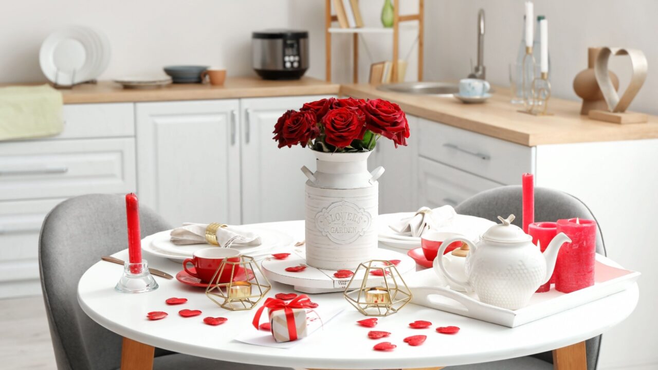 A dining table adorned with red roses and candles for a romantic setting.