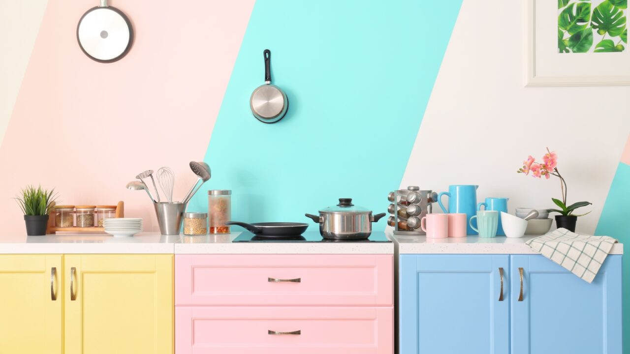 A colorful kitchen with pastel cabinets, various kitchen utensils, and cookware on the countertop.