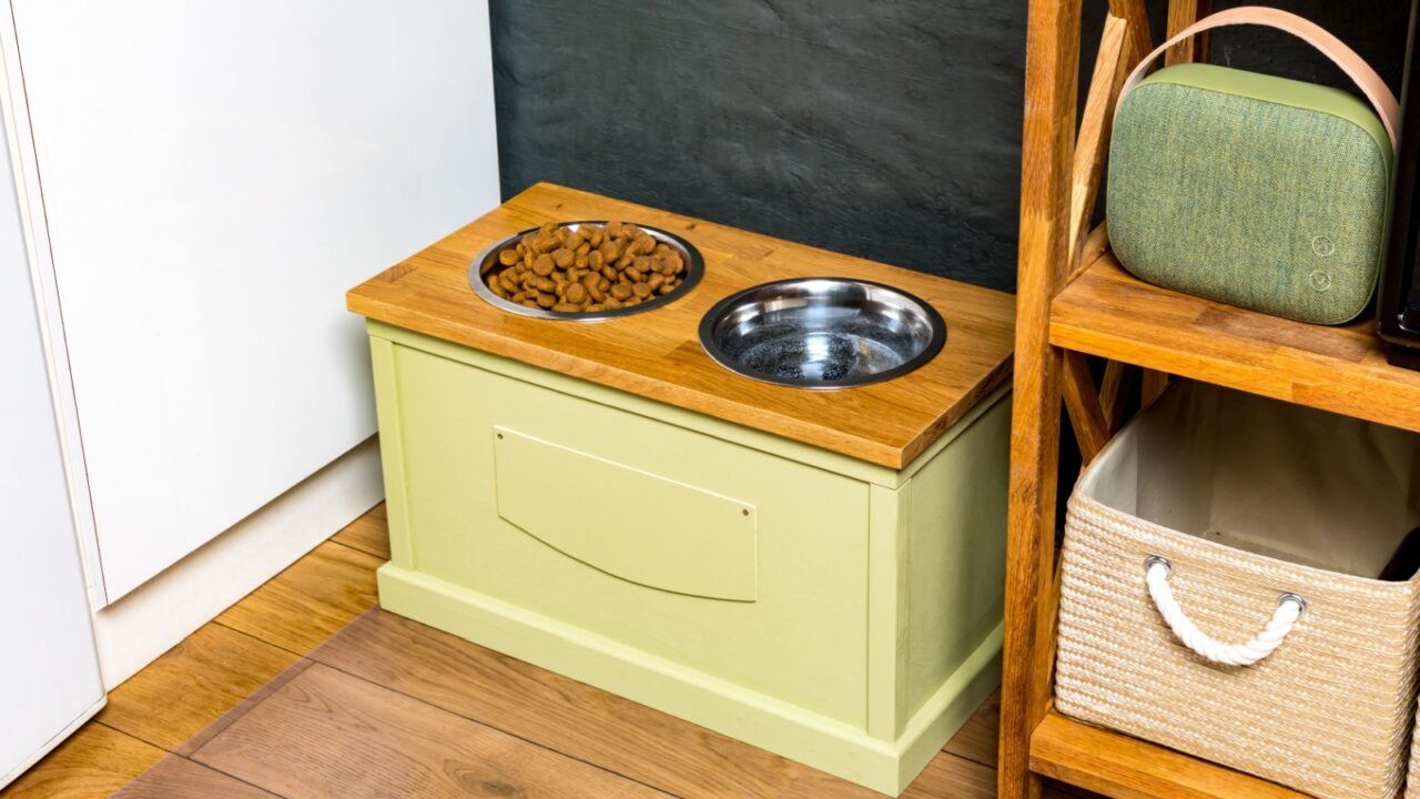 A built-in cabinet feeding station beside a wooden shelf containing baskets.