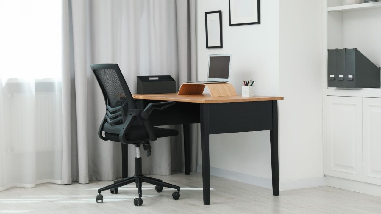 A home office interior with a sturdy desk with laptop and an ergonomic chair.