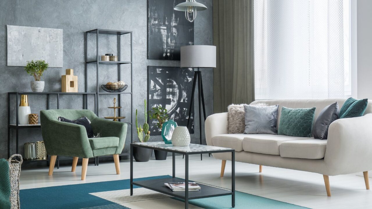 A modern living room interior with a white sofa, green armchair, wall art, shelf with decor accents, and a coffee table on rug.