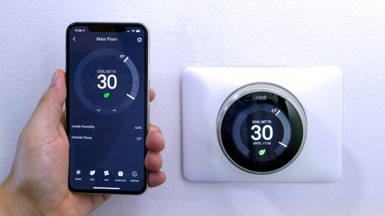 A person adjusting a smart thermostat using a smartphone.