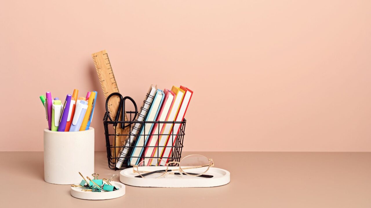 A pen holder and a metal diary holder on a pastel surface.