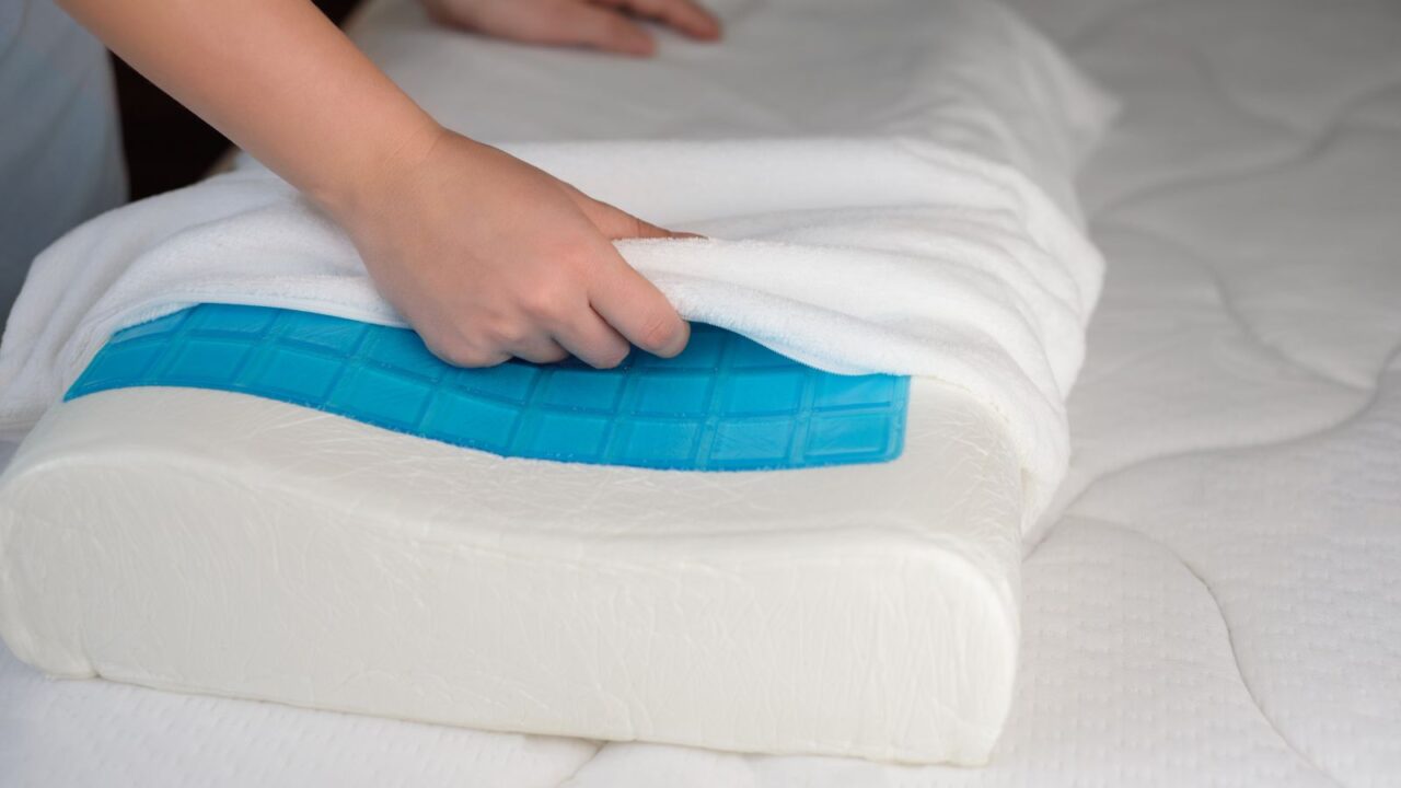 A woman putting a white pillow cover on a memory foam pillow.