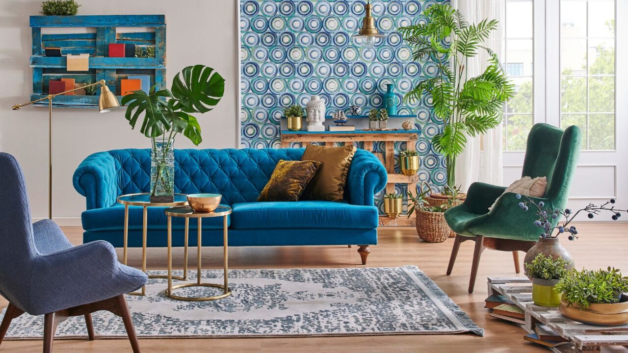 A stylish living room interior with blue sofa, armchairs, coffee table, potted plants, shelf, and a rug.