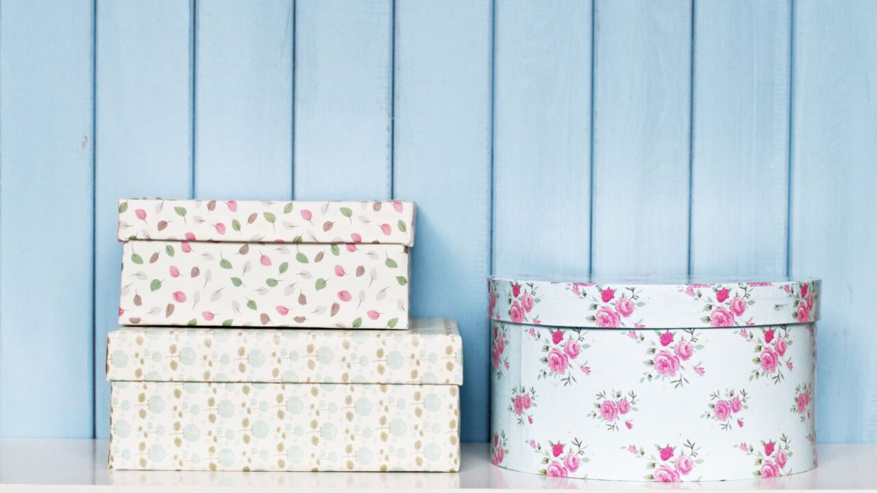 Decorative storage boxes on a white table in front of a blue wall.