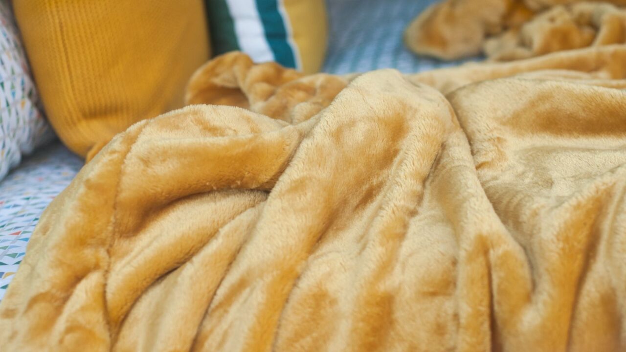 A cozy beige fleece blanket on the bed.