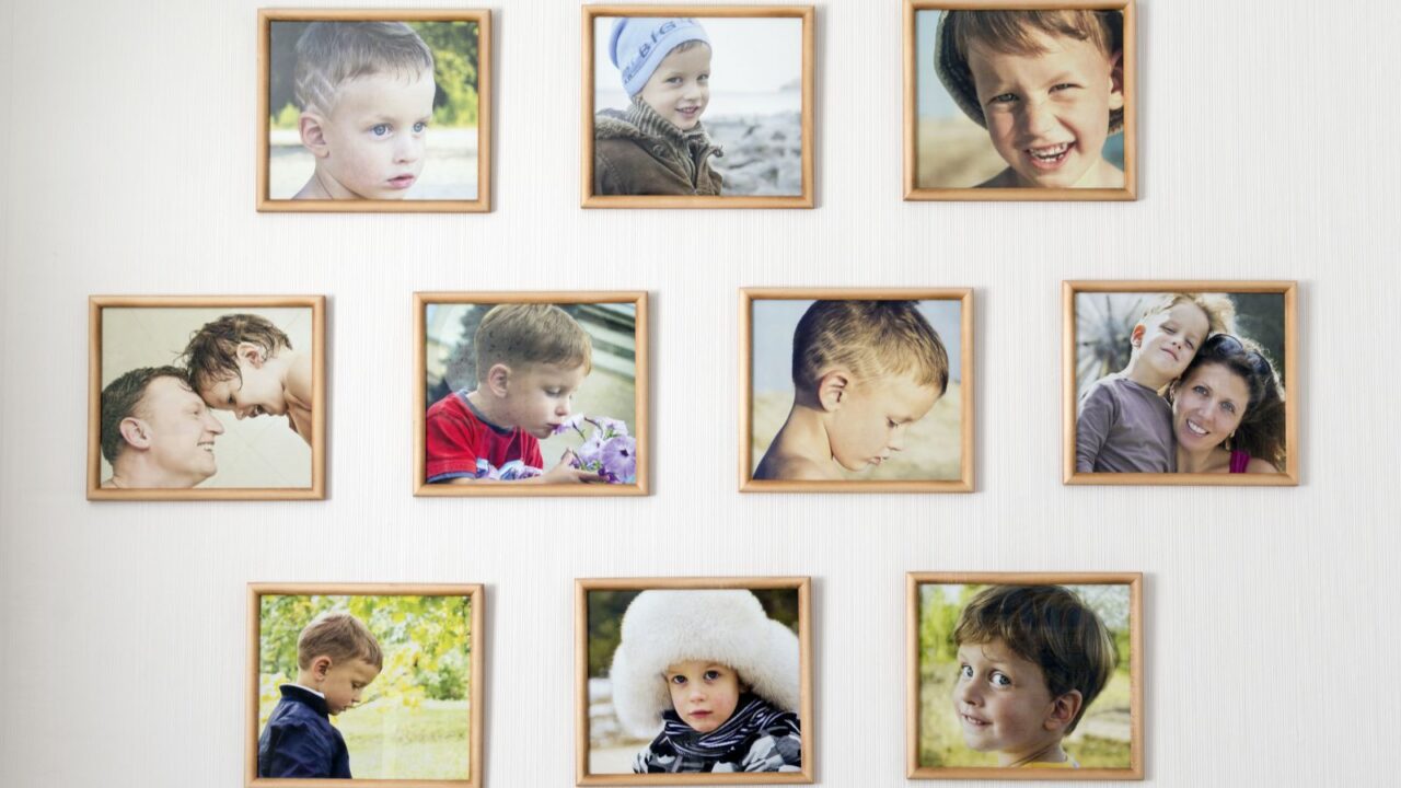 A white wall with family pictures in frames hanging on it.