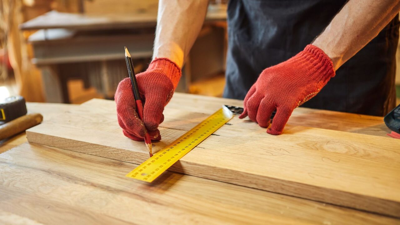 A man taking measurements of a wood plank.