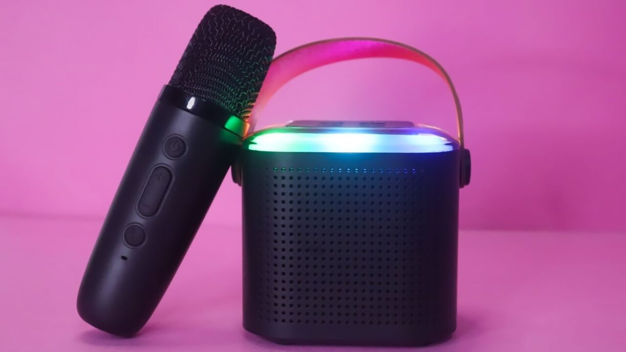 A bluetooth karaoke machine on a pink surface.