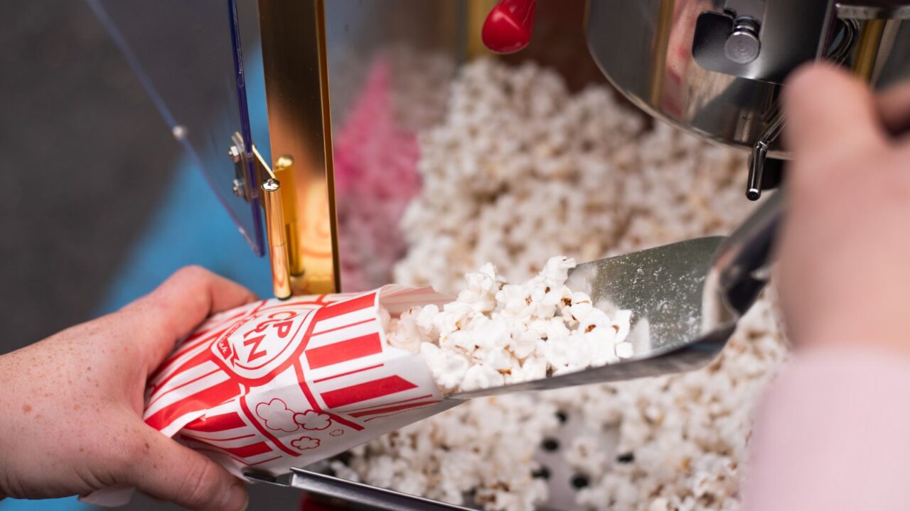 A person taking out popcorn from a popcorn machine.