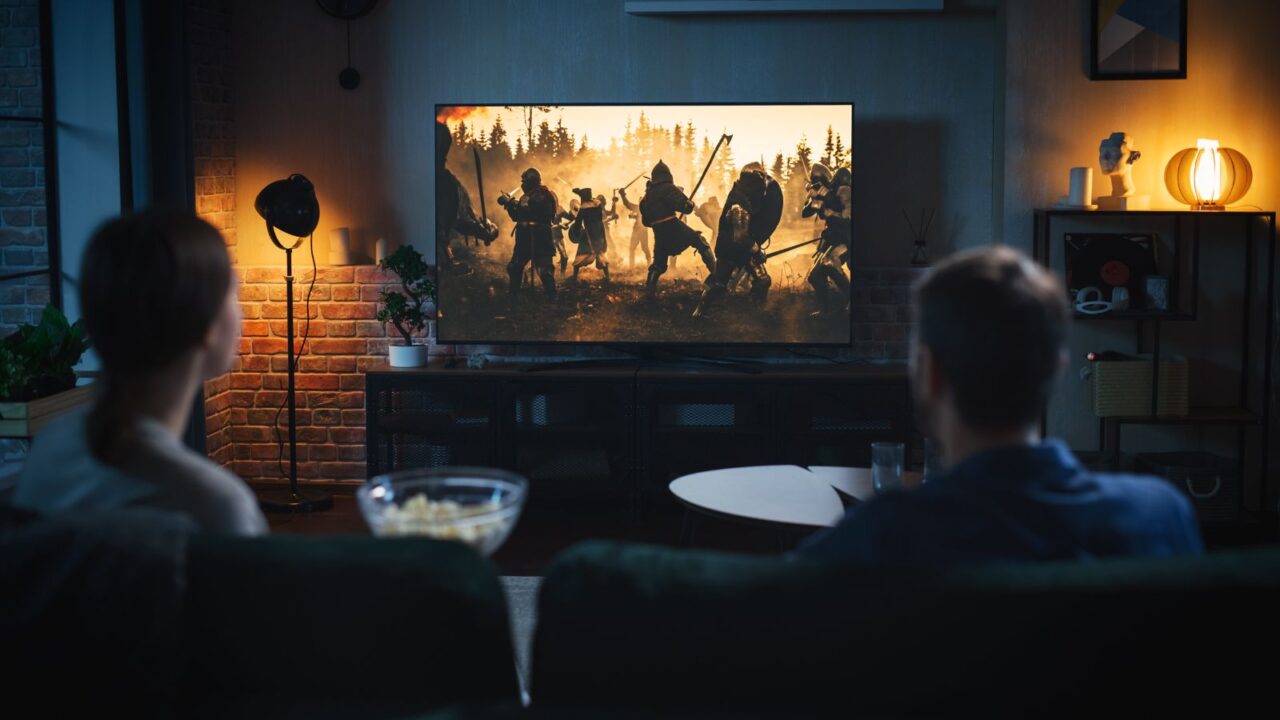 An entertainment room interior with a couple watching a show on the TV.