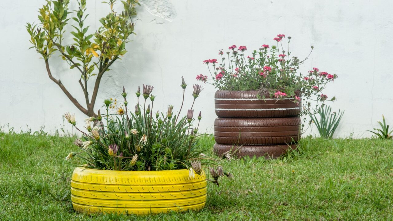 A beautiful garden with colorful tire planters on the grass.