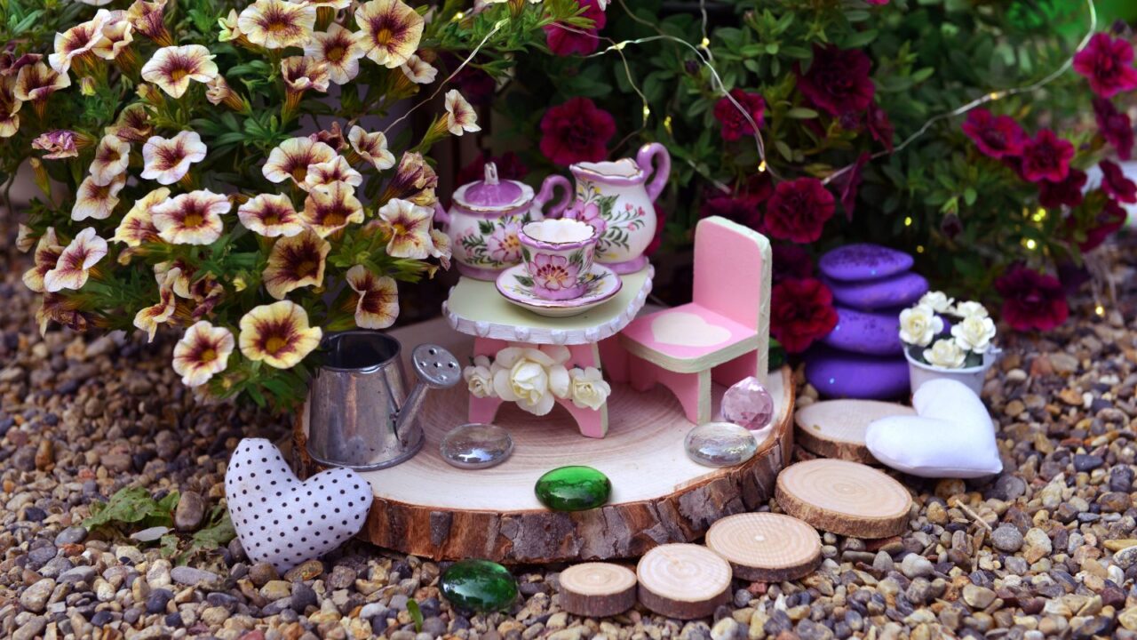 A lovely fairy party setup with little table, chair, tea set and decoration by petunia flowers in the garden.