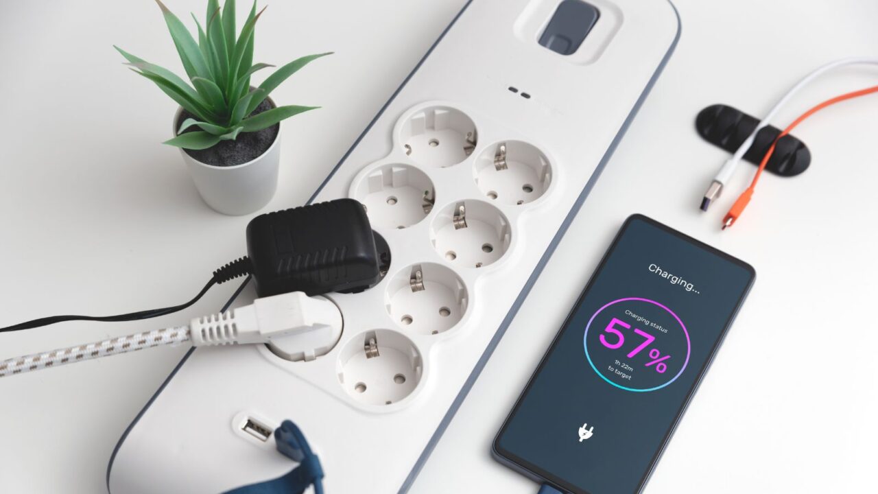 A mobile phone and power strip on a white table.