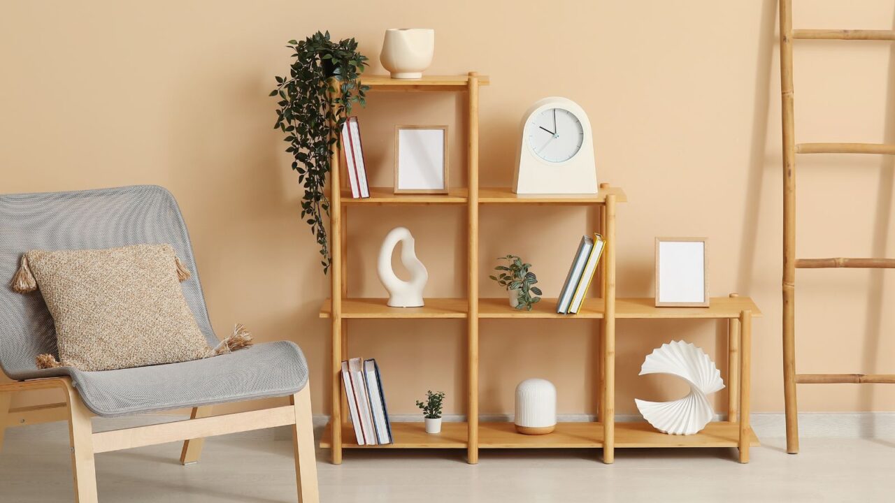 A reading nook with a chair, wooden ladder, and a wooden bookshelf with books, ceramic sculptures, clock, and small potted plants.