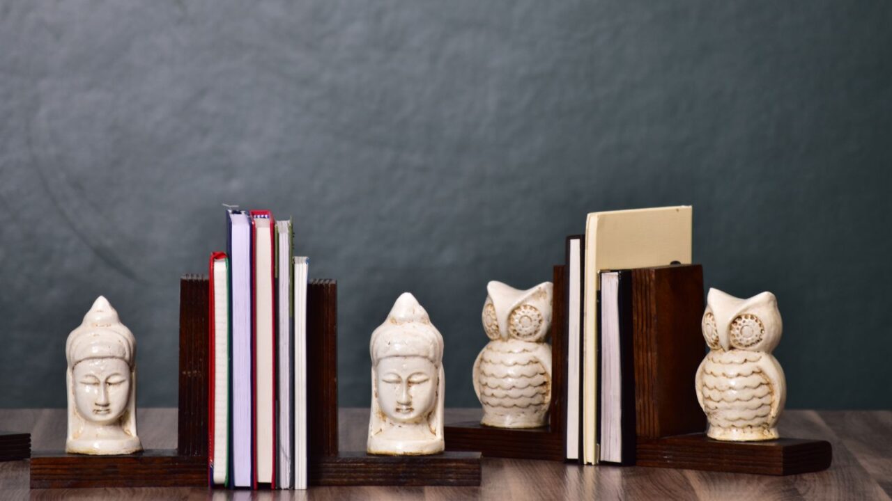 Bookends with ceramic figurines on a wooden surface in front of a gray wall.