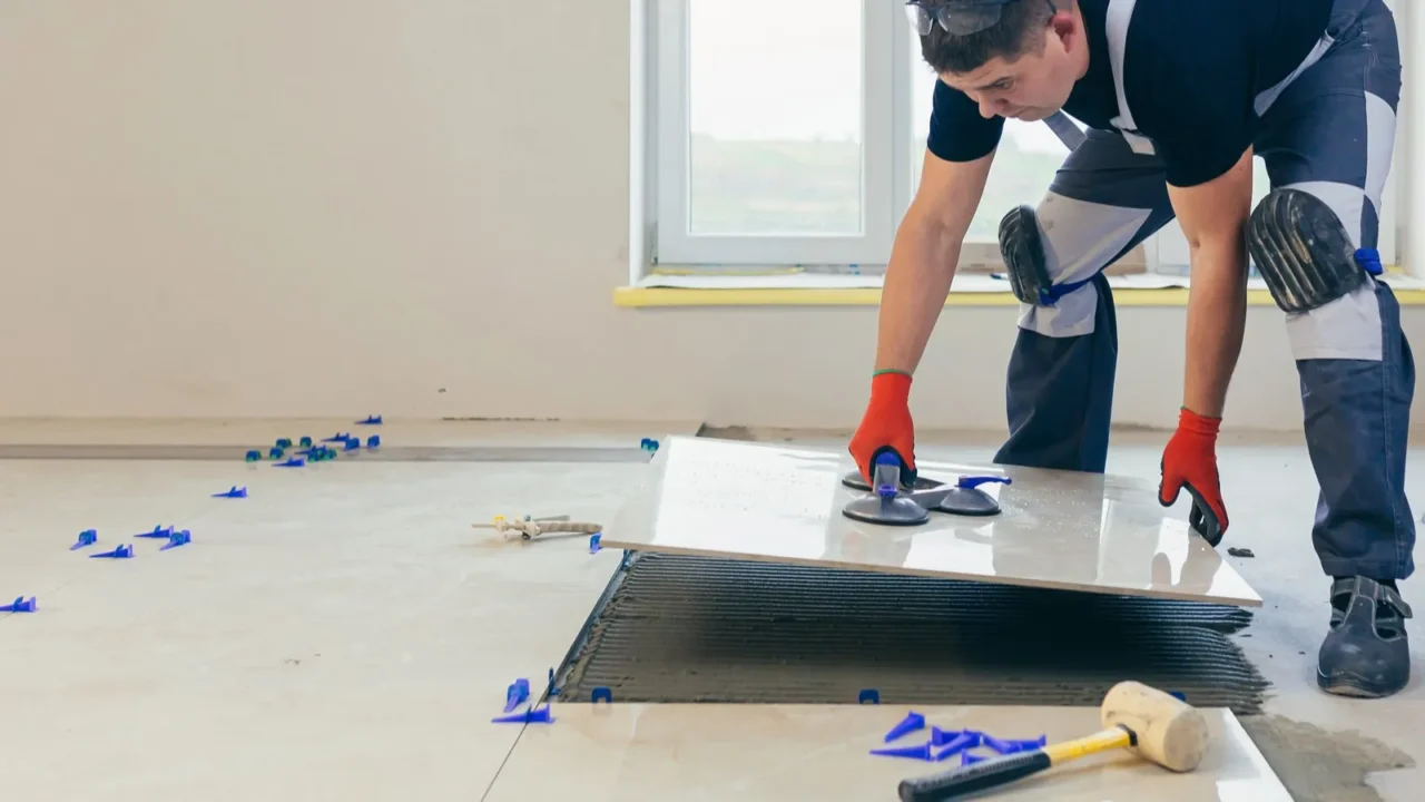 a male construction worker installs a large ceramic tile