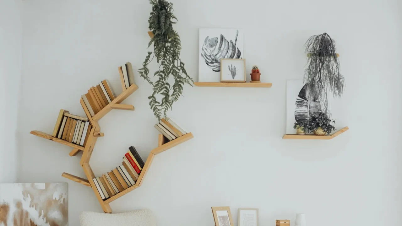 Wooden floating shelves with books, artwork, and small potted plants on them.