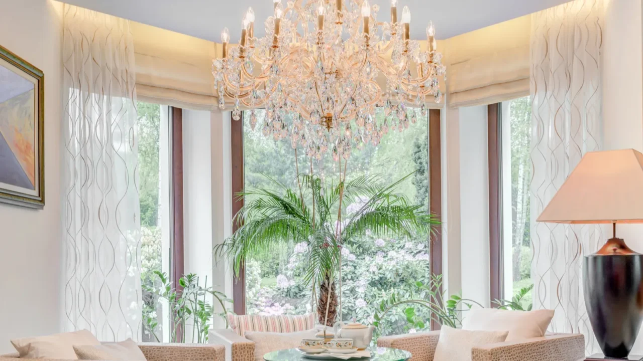 A bright living area with a chandelier, large windows, and a potted plant.