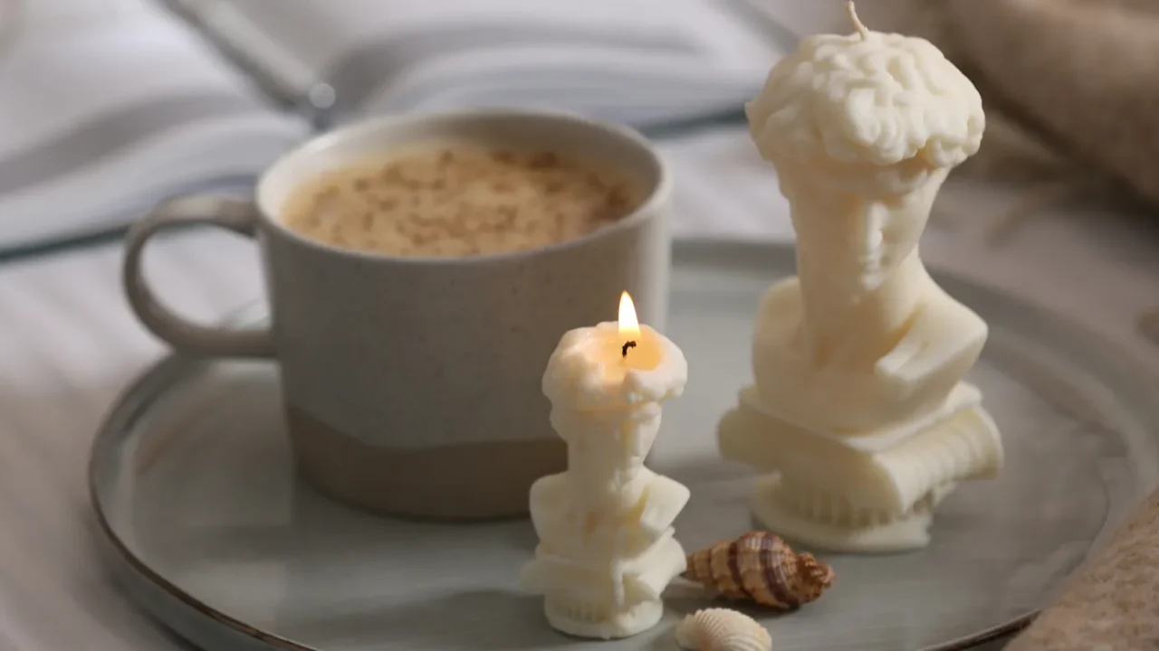 beautiful david bust candles seashells and cup of hot drink