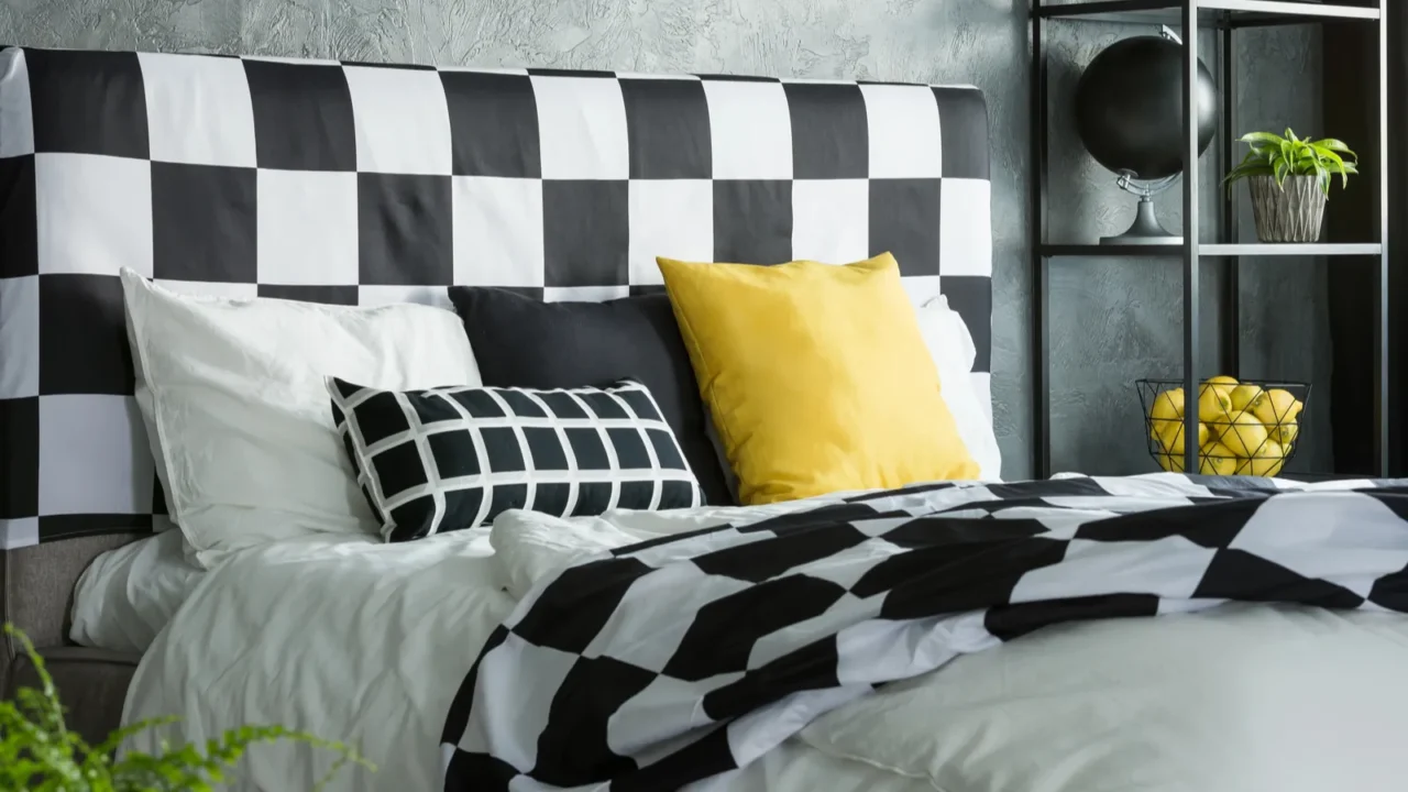 Black nd white patterned bedding on a gray bed.