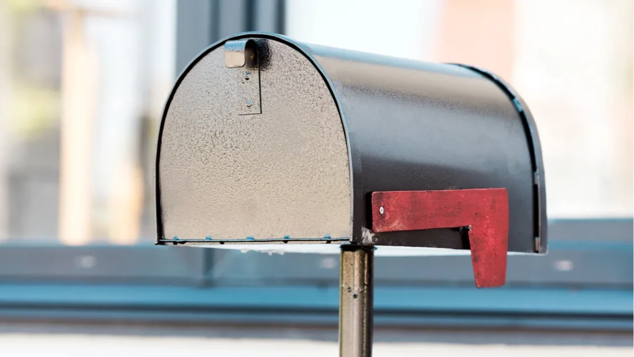 black metal mailbox near green bushes near house