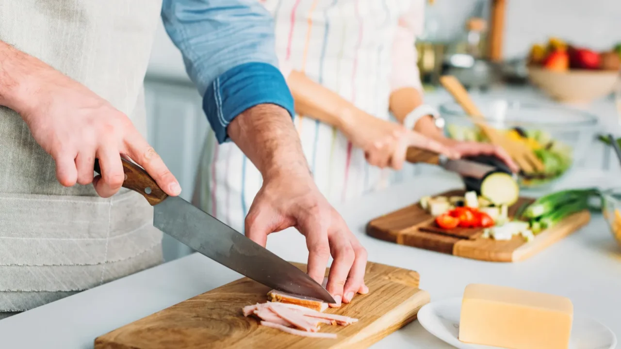 cropped image of couple cooking and cutting vegetables with meat