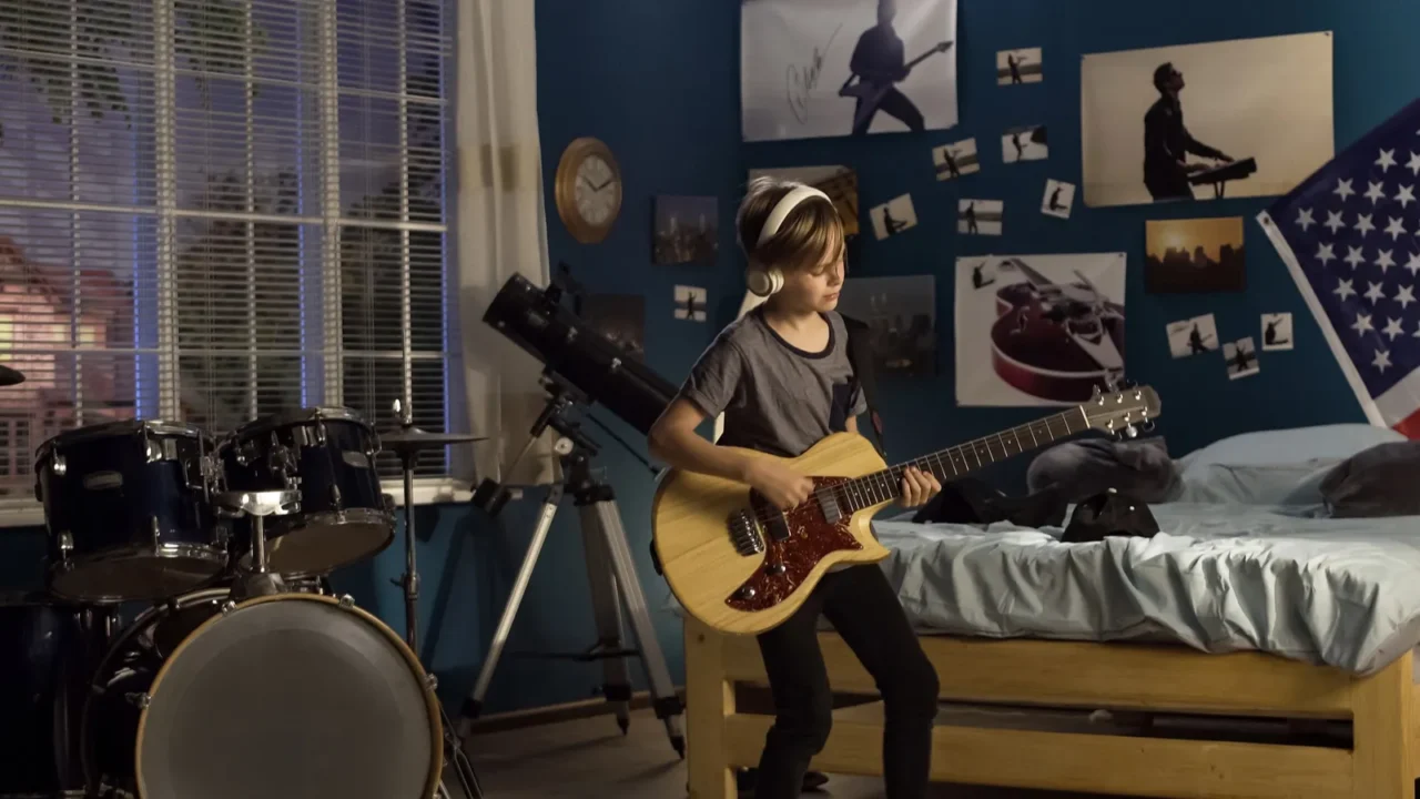 expressive youngster playing guitar in bedroom