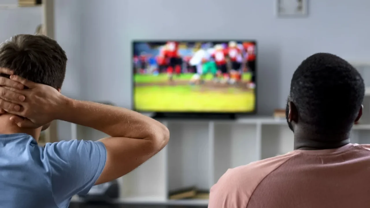 friends nervously watching american football competition on screen sofa experts