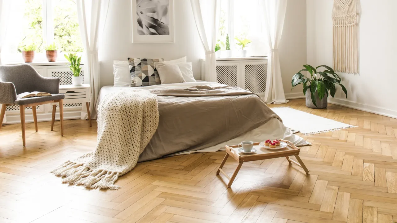 grey armchair next to bed with blanket in bright bedroom