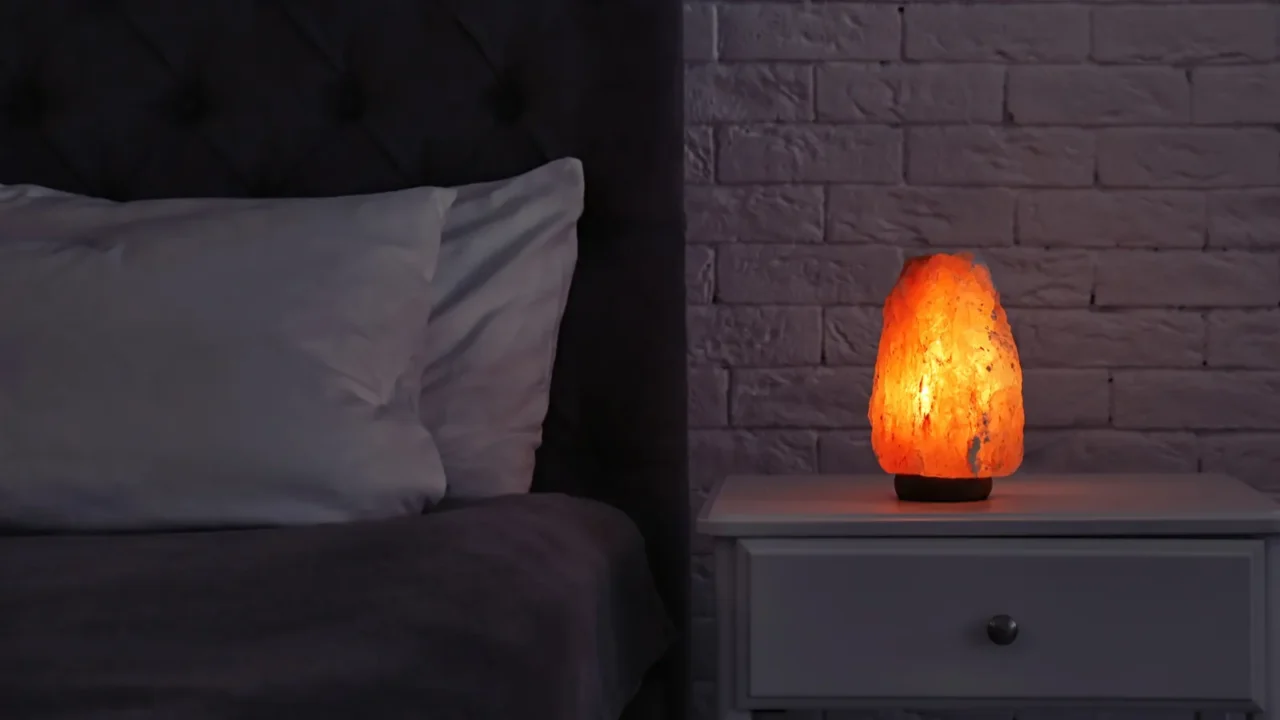 himalayan salt lamp glowing on bedside table in dark room