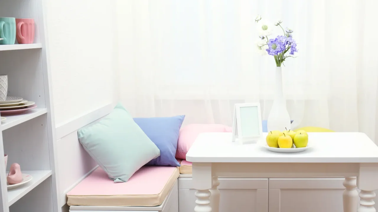 A breakfast nook in a kitchen near a window with cushioned bench and small table.