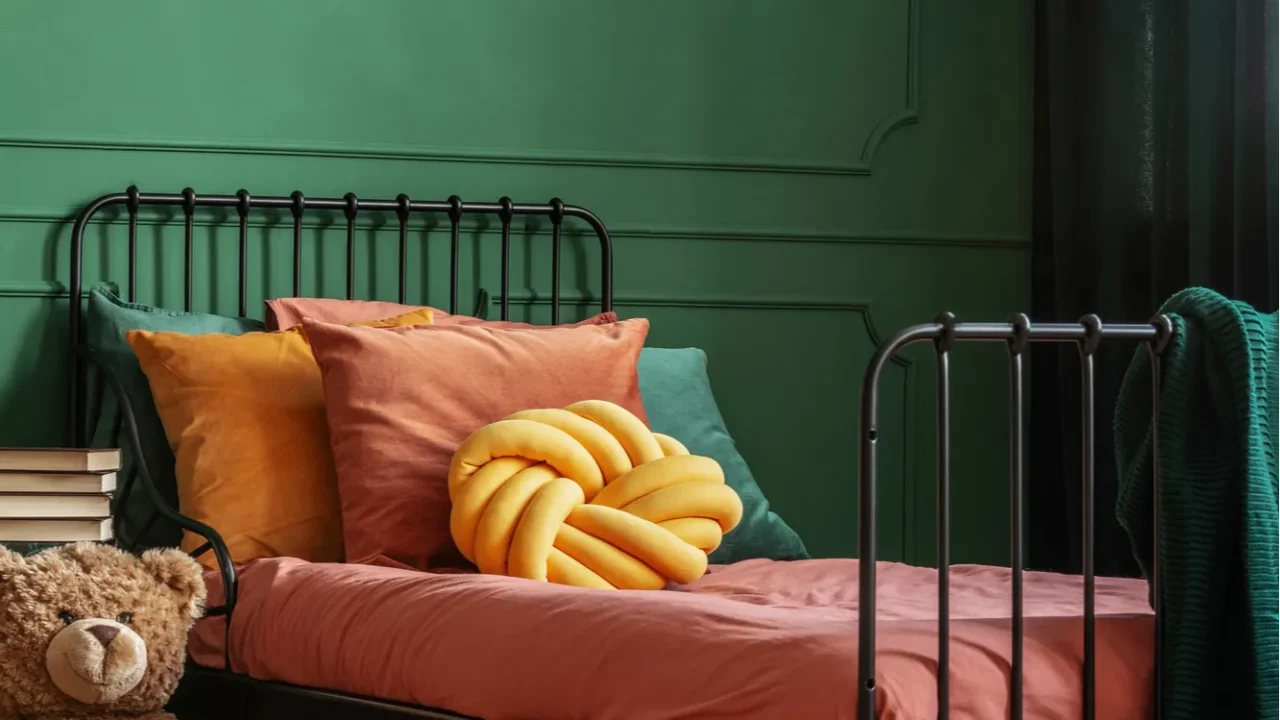 knot yellow pillow on single metal bed with dark orange