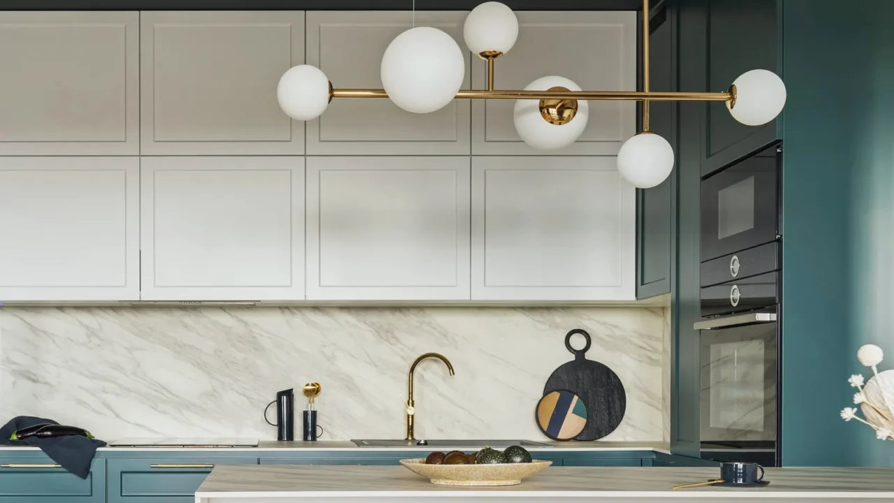 A modern kitchen interior with white cabinets, wooden countertop, ceiling pendant light, and smart appliances.