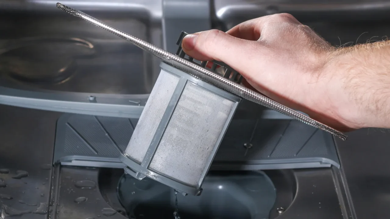 man unscrews the filter for cleaning in dishwasher