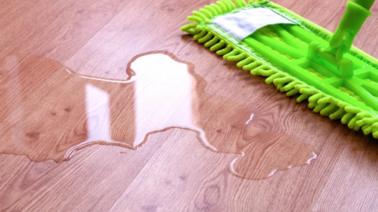 microfiber mop wiping puddle of water on laminate floor